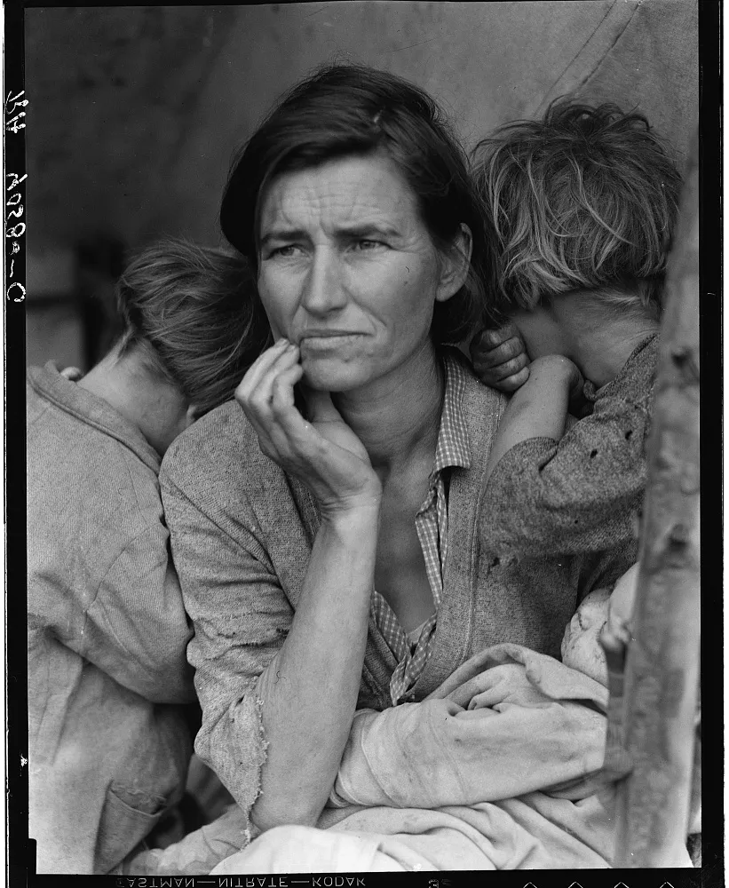 Black-and-white documentary photograph of a careworn migrant mother gazing into the distance, her hand to her face, with two children turning away against her shoulders and an infant in her lap, taken in a California pea-pickers' camp in 1936.