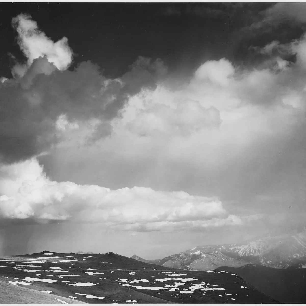 Black-and-white photograph of clouds gathering over a mountain ridge